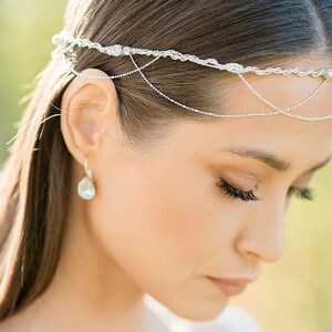 May include: A silver chain headpiece with delicate, beaded details. The headpiece is worn by a person with long, dark hair.
