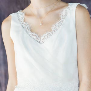 May include: A white sleeveless dress with a lace trim around the neckline and hem. The dress has a simple, elegant design and is perfect for a special occasion.
