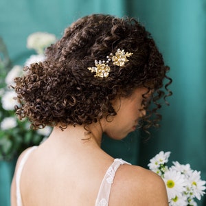 A beautiful pair of simple bridal hair pins with an oversized floral bloom, enamel painted centres and pearls.  Each flower is accented with sprigs of round glass pearls, sparkling crystals and oak leaves. Handmade in Toronto Canada by Blair Nadeau