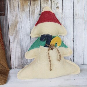 May include: A white felt Christmas tree with red, white, and green stripes. The tree has a pocket on the front with a yellow and blue candy cane inside.