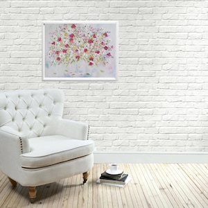 K&ouml;nnte beinhalten: Ein wei&szlig;er Sessel mit Kn&ouml;pfen steht vor einer wei&szlig;en Backsteinwand. An der Wand h&auml;ngt ein gerahmtes Bild mit einem Strau&szlig; wei&szlig;er und rosa Blumen in einer Vase. Vor dem Sessel liegen auf dem Boden ein Stapel B&uuml;cher und eine Tasse Kaffee.