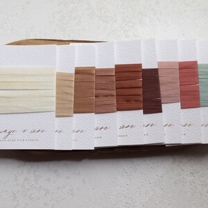 May include: A color palette of silk ribbons in various shades of beige, brown, and muted colors, displayed on white cards. The cards are arranged on a wooden tray. The text "fringe + rose" and "HAND-DYED SILK RIBBON" is visible.