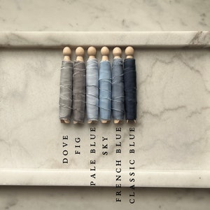 May include: Six spools of ribbon in various shades of blue and gray, labeled with their color names: Dove, Fig, Pale Blue, Sky, French Blue, and Classic Blue.