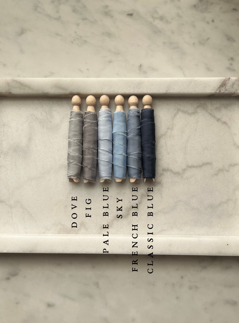 May include: Six spools of ribbon in various shades of blue and gray, labeled with their color names: Dove, Fig, Pale Blue, Sky, French Blue, and Classic Blue.