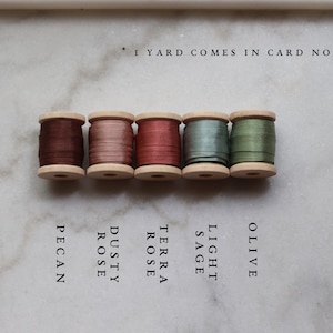 May include: Five wooden spools of silk ribbon in shades of brown, pink, and green. Colors include Pecan, Dusty Rose, Terra Rose, Light Sage, and Olive. Text reads: *1 YARD COMES IN CARD NOT SPOOL.