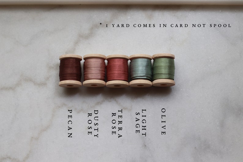 May include: Five wooden spools of silk ribbon in shades of brown, pink, and green. Colors include Pecan, Dusty Rose, Terra Rose, Light Sage, and Olive. Text reads: *1 YARD COMES IN CARD NOT SPOOL.