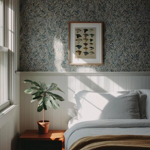 K&ouml;nnte beinhalten: Ein Schlafzimmer mit wei&szlig;en W&auml;nden und einem Bett mit wei&szlig;en Bettw&auml;sche und einer braunen Decke. Ein gerahmtes Bild von V&ouml;geln h&auml;ngt an der Wand &uuml;ber dem Bett. Eine Topfpflanze steht auf einem Holz-Beistelltisch.