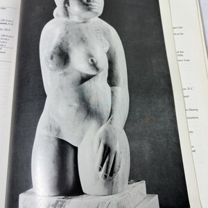 May include: A black and white photograph of a marble sculpture depicting a torso of a figure with a smooth, rounded head and defined facial features. The figure is shown from the waist up, resting on a rectangular marble base within a book page.