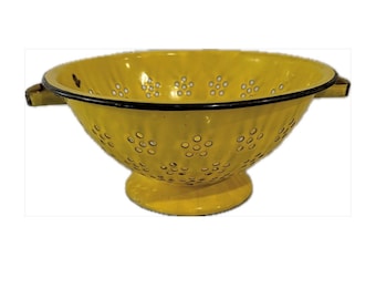 May include: Yellow enamel colander with black rim and small flower-shaped holes. The colander has two handles and a pedestal base.