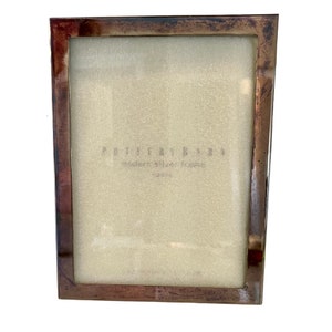May include: A silver picture frame with a distressed finish. The frame is made by Pottery Barn and is labeled "Modern Silver Frame".