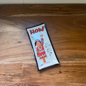 May include: A white ceramic dish with a black rim features a cartoon illustration of a person in a red and white patterned dress with the text "HOW ABOUT GETTING WELL QUICK?"