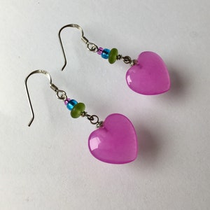 May include: A pair of silver heart-shaped earrings with pink glass hearts and blue and green glass beads.