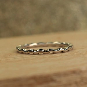 May include: A silver ring with a wavy, textured band.