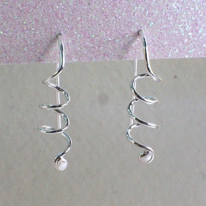May include: A pair of silver spiral earrings with a small round bead at the end of each spiral.