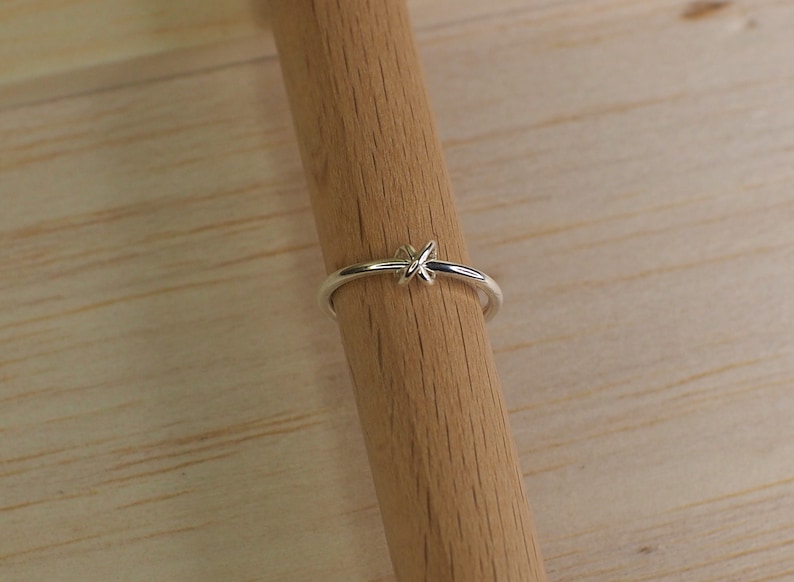 A silver fidget ring with a free moving bead in a knot design.