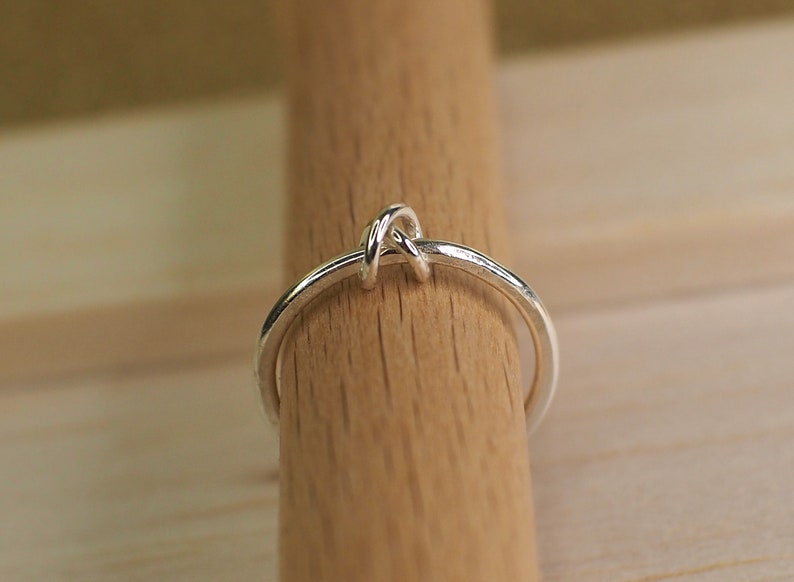 A simple sterling silver beaded fidget ring on a wooden surface.