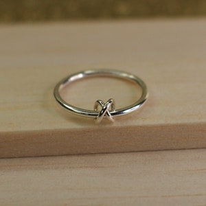 A silver spinning ring with a criss-cross knot bead.