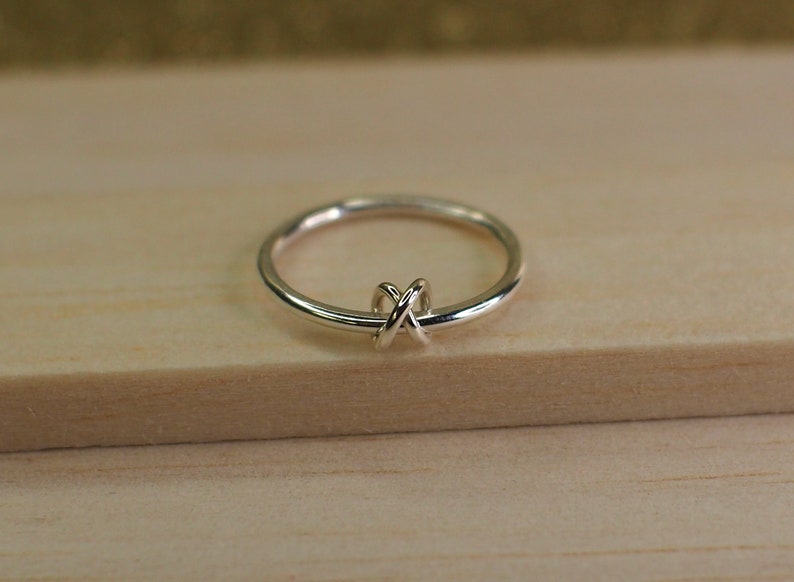 A silver spinning ring with a criss-cross knot bead.