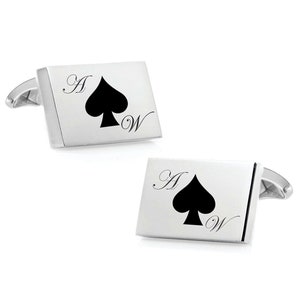 May include: A pair of silver cufflinks with a black spade design and the letters "A" and "W" engraved on each cufflink.