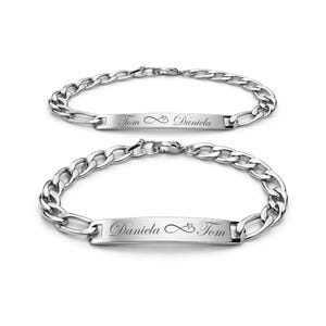 May include: Two silver-colored bracelets with a chain link design. Each bracelet has a rectangular plate with engraved text. One reads "Tom ∞ Daniela", the other reads "Daniela ∞ Tom". The bracelets are displayed on a white background.