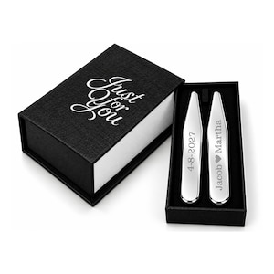 May include: A black rectangular gift box with the text Just for You printed in white on the lid. Inside the box are two silver-toned metal collar stays. One stay is engraved with 4-8-2027 and the other with Jacob heart Martha.