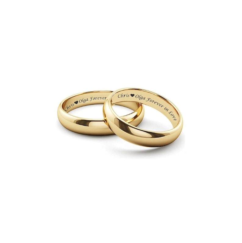 Puede incluir: Dos alianzas de boda doradas, una superpuesta a la otra, sobre un fondo blanco. El interior de cada anillo est&aacute; grabado con un nombre, un s&iacute;mbolo de coraz&oacute;n y las palabras "Forever" o "Forever in Love".