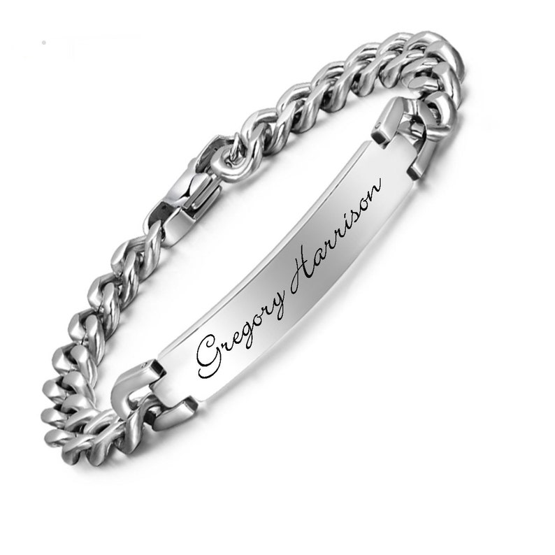 May include: A silver-colored bracelet with a curb chain design. The bracelet features a rectangular plate engraved with the name "Gregory Harrison" in a cursive font. The clasp is visible, and the bracelet is set against a white background.