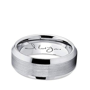 May include: A silver-colored ring with a brushed center band and polished edges. The inner band features the handwritten phrase "I love you." The ring has a modern, minimalist design.