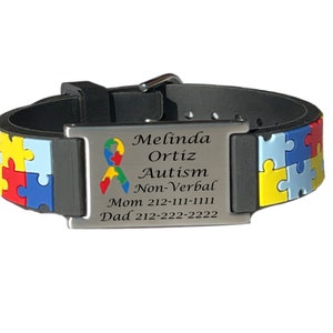 May include: A black and silver medical alert bracelet with a puzzle piece design in primary colors. The bracelet has a metal plate with the name "Melinda Ortiz", the word "Autism", and contact information.