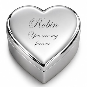 May include: A heart-shaped, silver-colored trinket box. The lid is engraved with the name "Robin" and the phrase "You are my forever" in elegant script. The box has a polished, reflective surface.
