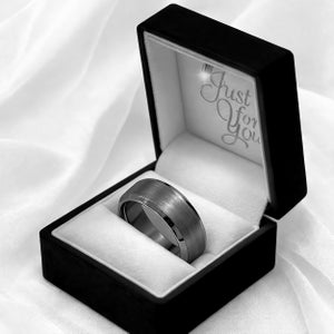 May include: A silver-colored ring with a brushed metal finish, presented in a black box with a white interior. The box is open, revealing the ring nestled on a white cushion. The text "Just For You" is visible inside the box.