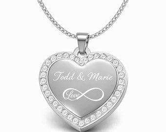 May include: A silver heart-shaped pendant necklace. The pendant is engraved with the names "Todd & Marie" and the word "Love" with an infinity symbol. The pendant is encrusted with small, clear crystals around the edge.
