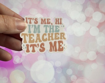 May include: A white sticker with the text "It's me, hi I'm the teacher It's me" in a retro font. The text is in shades of pink, orange, and blue.