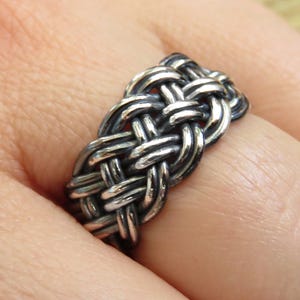 May include: A silver braided ring with a woven design.