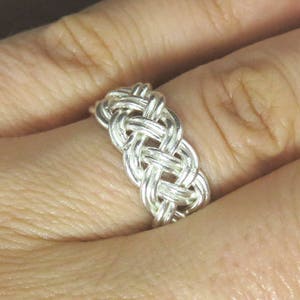 May include: A silver braided ring with a woven design.