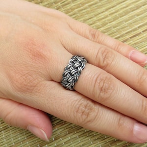 May include: A silver braided ring with a woven design.