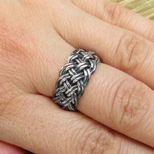 May include: A silver braided ring with a woven design.