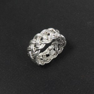 May include: A silver braided ring with a woven design.