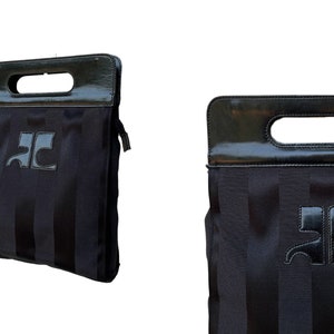May include: Black tote bag with vertical stripes and a glossy black handle. The bag features a logo on the front. The handle has a rectangular opening for carrying. The bag is a dark color.
