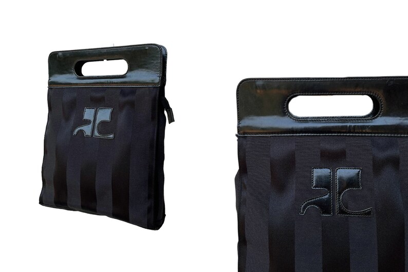 May include: Black tote bag with vertical stripes and a glossy black handle. The bag features a logo on the front. The handle has a rectangular opening for carrying. The bag is a dark color.