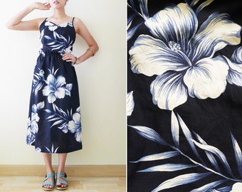 Könnte beinhalten: Ein marineblaues Midikleid mit weißem Blumenmuster. Das Kleid hat einen runden Ausschnitt und dünne Träger. Das Kleid ist aus einem leichten Stoff gefertigt und hat eine lockere Passform.