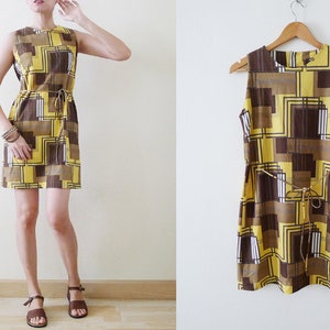 May include: A sleeveless yellow and brown geometric print mini dress with a tie at the waist. The dress is shown on a model and on a hanger.