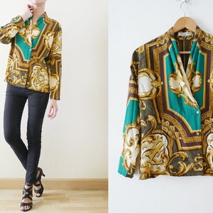 Może przedstawiać: Długa koszula z zielonym, brązowym i złotym wzorem. Wzór zawiera ozdobne detale i geometryczny projekt.