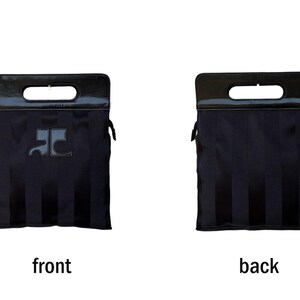 May include: Black tote bag with a rectangular handle and a dark, glossy finish. The front of the bag features a logo, and the back has vertical stripes. The bag is designed with a structured shape and a sleek, modern aesthetic.
