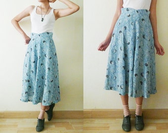 May include: A blue and white patterned skirt with a high waist and a flowing silhouette. The skirt is made of a lightweight fabric and has a subtle swirl design.