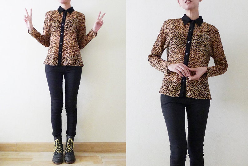 Op de afbeelding: Een doorschijnend overhemd met luipaardprint, zwarte knopen en een zwarte kraag. Het overhemd wordt gedragen met een zwarte skinny jeans en zwarte combat boots.