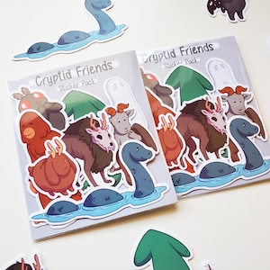 Könnte beinhalten: Zwei Stickerpackungen mit dem Titel "Cryptid Friends Sticker Pack" werden gezeigt, umgeben von einzelnen Aufklebern. Die Aufkleber zeigen verschiedene Kryptiden im Cartoon-Stil, darunter ein Seeungeheuer, ein Bigfoot und ein Geist. Die Farbpalette umfasst Brauntöne, Blau und Grün.