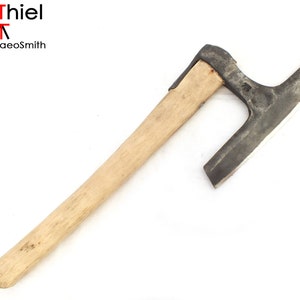 Peut inclure: Une hache traditionnelle forgée à la main avec un manche en bois. La tête de la hache est incurvée et possède une lame tranchante. Le manche est en bois clair.
