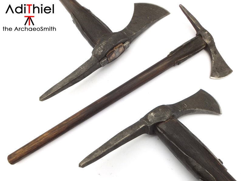 May include: Three views of a medieval style axe with a wooden handle. The axe has a pick on one side and a blade on the other. The axe is made of metal and has a dark brown wooden handle. The axe is displayed on a white background. AdiThiel the Archaeosmith is printed on the background.