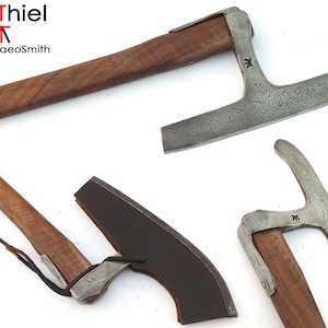 Peut inclure: Plusieurs haches artisanales avec des manches en bois et des lames en métal à motifs. Les haches varient en taille et en design, mettant en valeur le savoir-faire détaillé. Le texte "AdiThiel" et "the ArchaeoSmith" est visible.